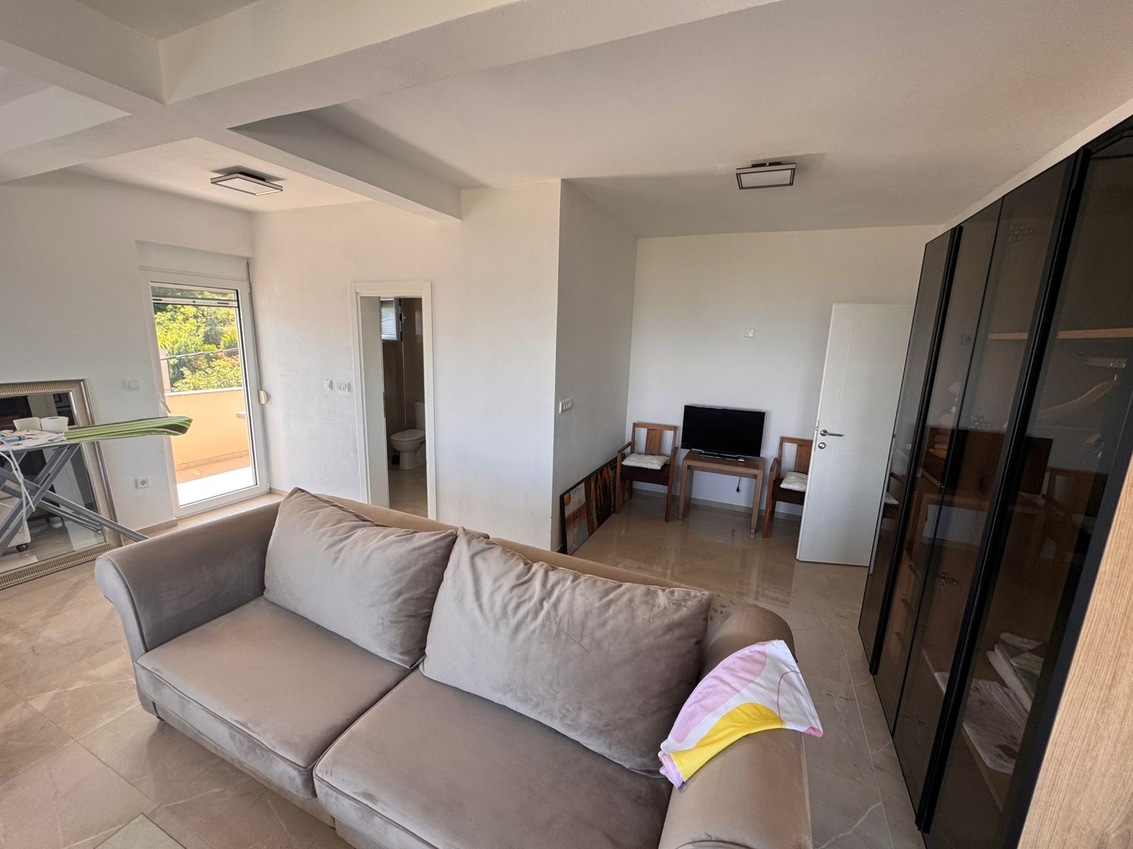 Modern Ulcinj apartment: bright living room, chic beige sofa, balcony access, and bathroom&mdash;exclusive on immobilien.ekosphere.me by ekosphere.