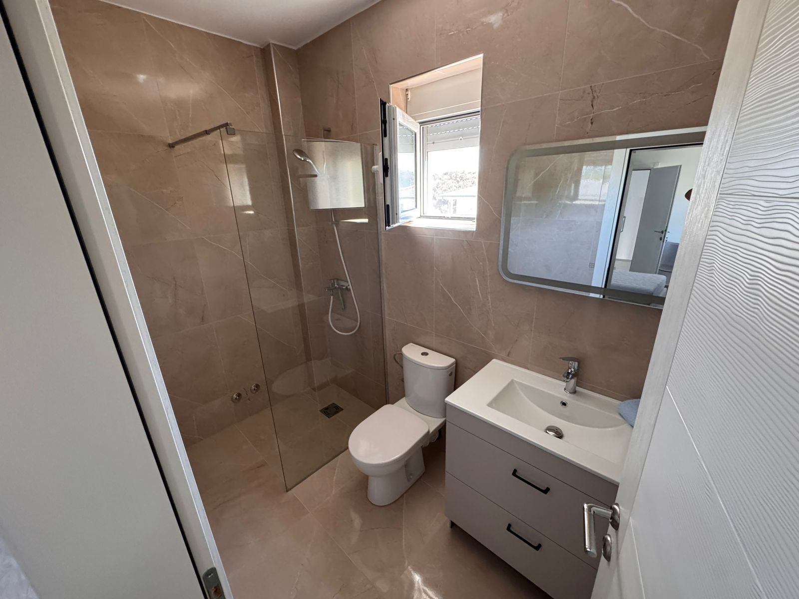Luxurious Ulcinj bathroom: beige marble, glass shower, modern sink, bright window&mdash;exclusive at immobilien.ekosphere.me by ekosphere doo.