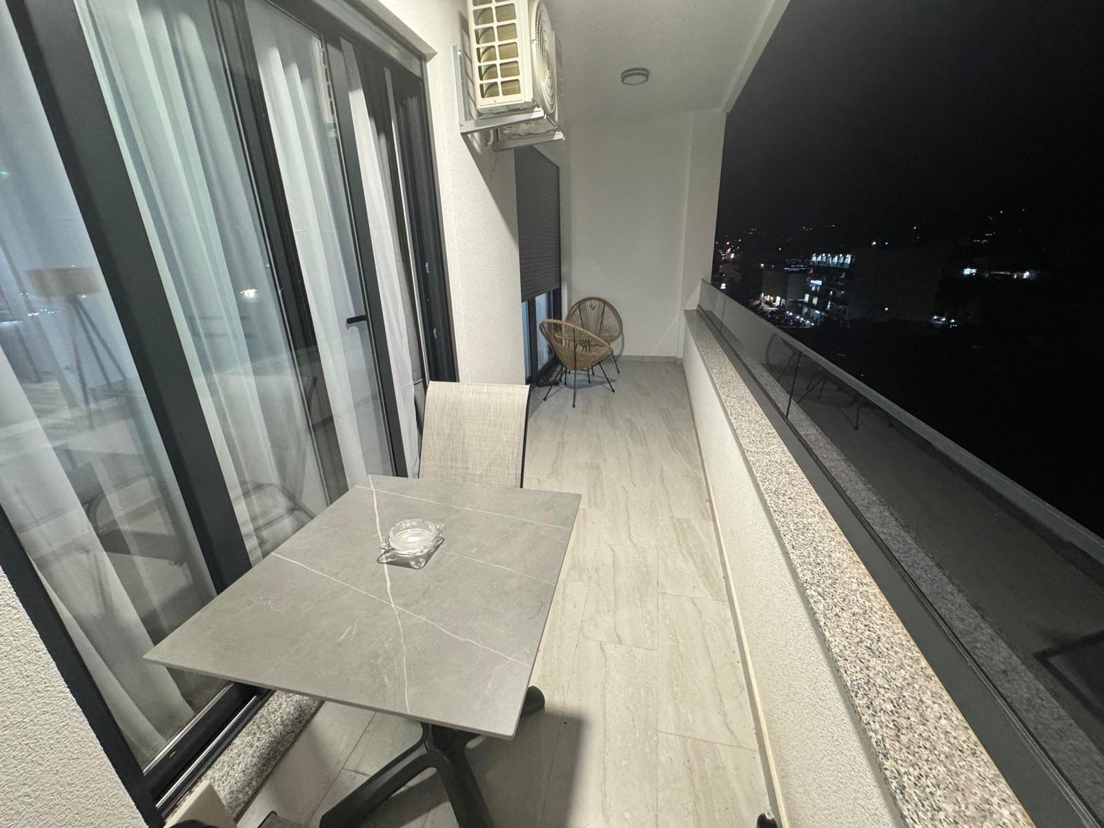 Luxury Ulcinj balcony: marble table, air conditioning, chic wicker seating, city views. Prime investment on immobilien.ekosphere.me.