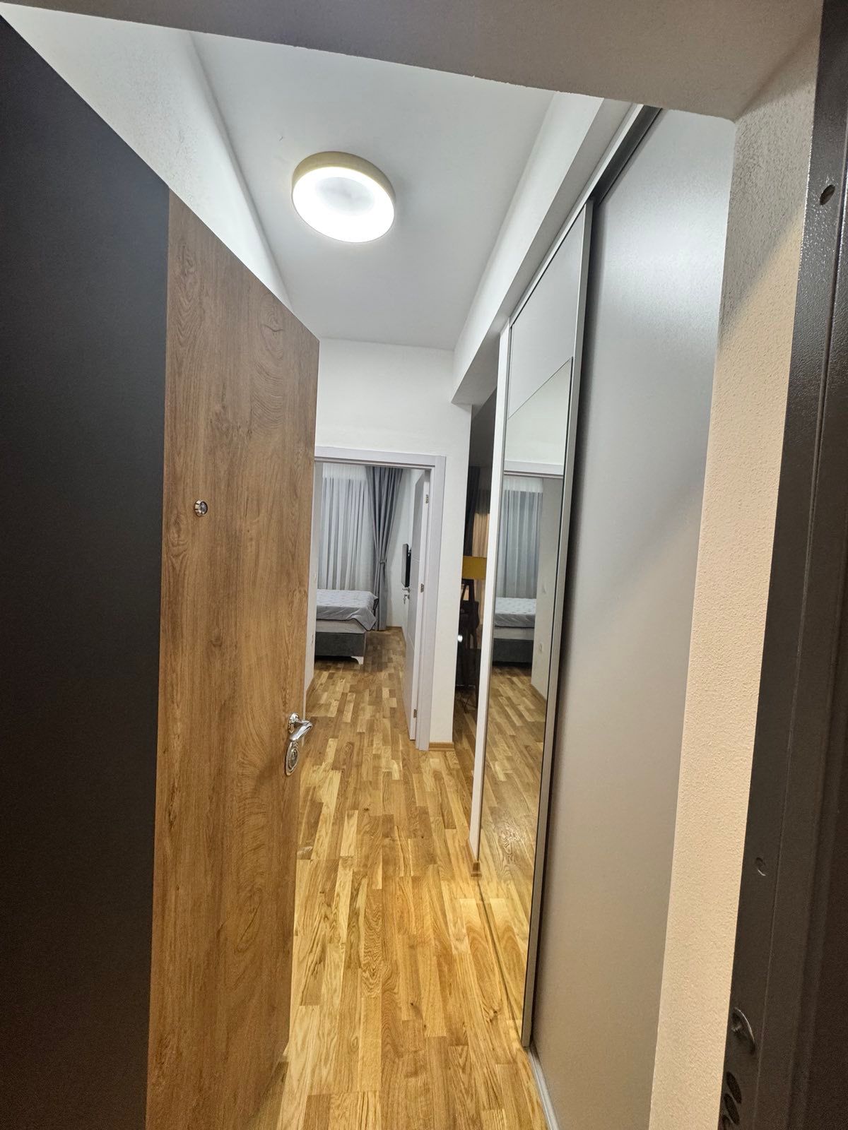 Elegant Ulcinj apartment hallway with wood floors, mirrored closets, spacious bedroom. Invest via immobilien.ekosphere.me by ekosphere doo.