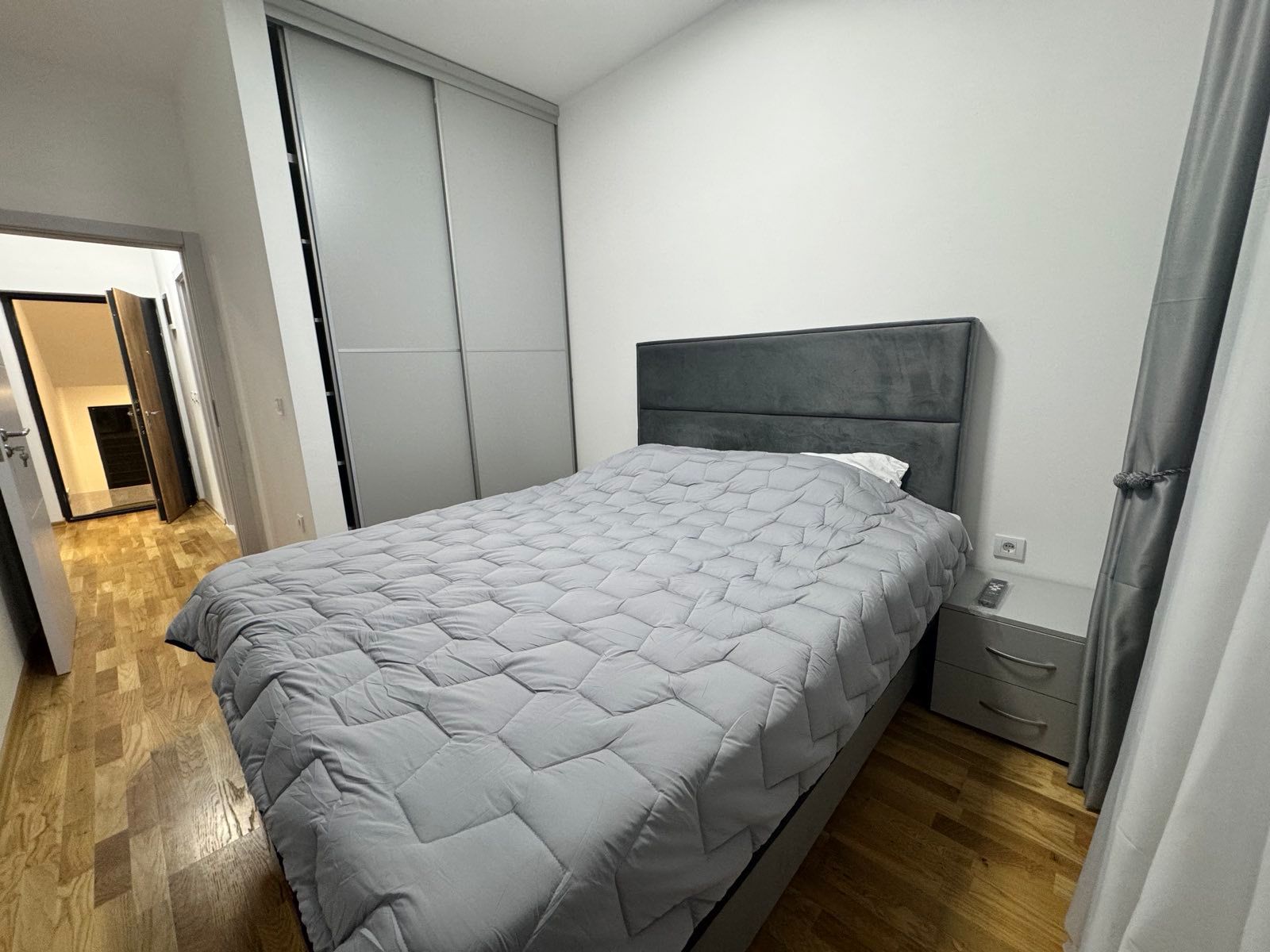 Elegant Ulcinj bedroom with stylish gray-quilted bed, hardwood floors, spacious closets&mdash;ideal Montenegro investment via immobilien.ekosphere.me by ekosphere doo.