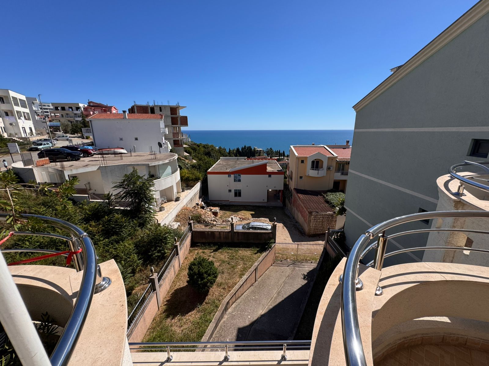 Stunning Ulcinj balcony view: peaceful homes, lush greenery, road to blue sea. Prime Montenegro real estate by ekosphere doo.