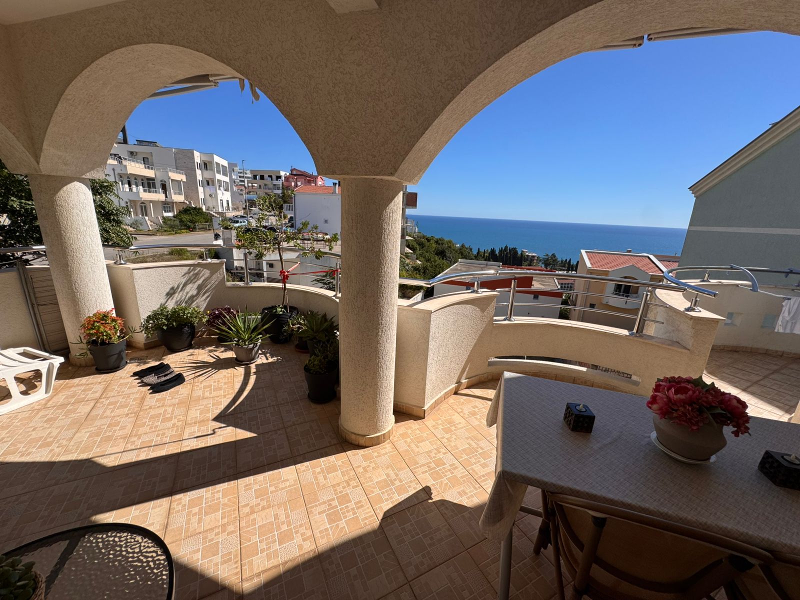 Spacious tiled balcony in Ulcinj with sea view, stylish columns, lush potted plants&mdash;exclusive property by immobilien.ekosphere.me.