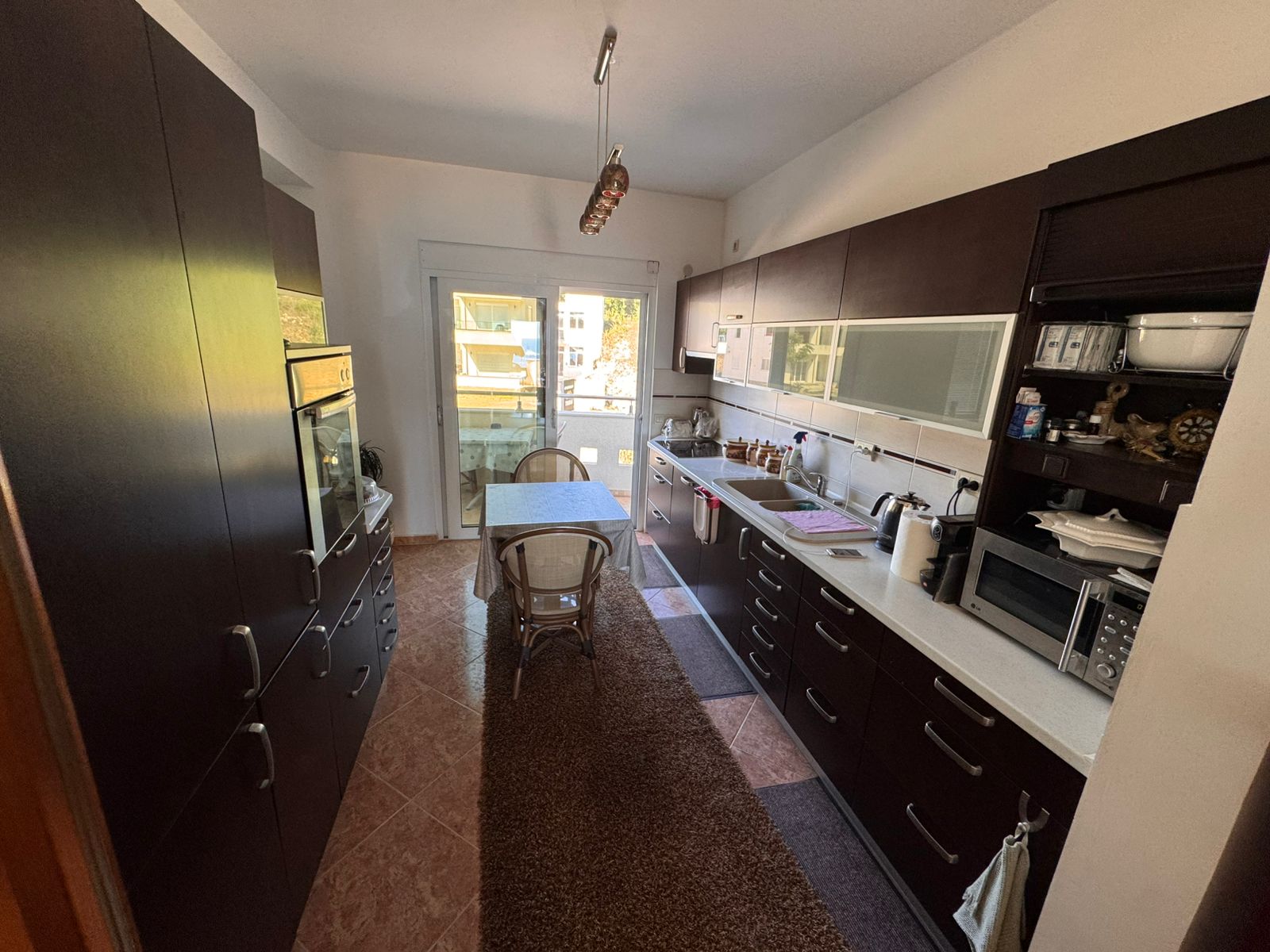 Elegant Ulcinj kitchen with sleek dark cabinets, sunlit dining area, premium appliances&mdash;ideal Montenegro property investment. Exclusive by ekosphere doo via immobilien.ekosphere.me.
