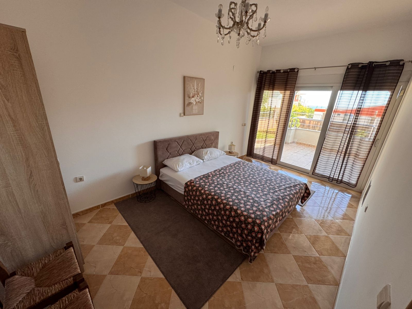 Elegant Ulcinj bedroom: double bed, nightstands, chandelier, checkered floors, balcony with views&mdash;exclusive at immobilien.ekosphere.me by ekosphere doo.