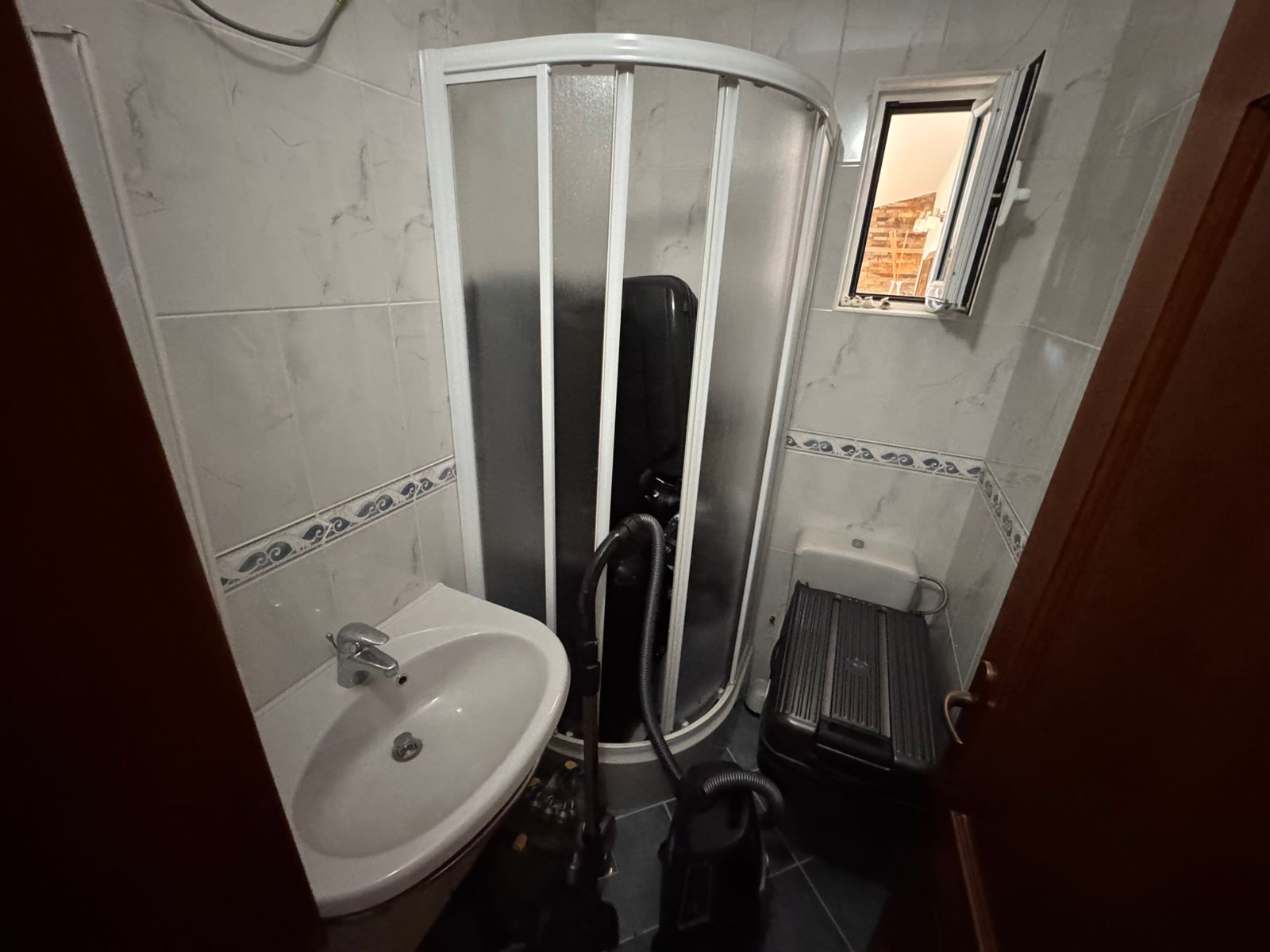 Modern Ulcinj bathroom with corner shower, open window, white-blue tiles; perfect buy-to-let on immobilien.ekosphere.me by ekosphere doo.