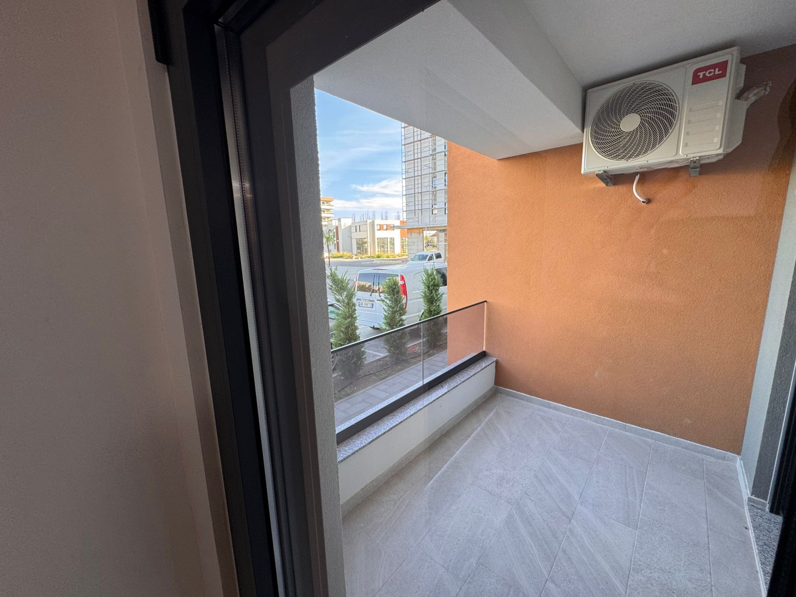 Modern tiled balcony in Ulcinj with glass railing, AC, and urban views&mdash;prime Montenegro real estate by ekosphere doo on immobilien.ekosphere.me.