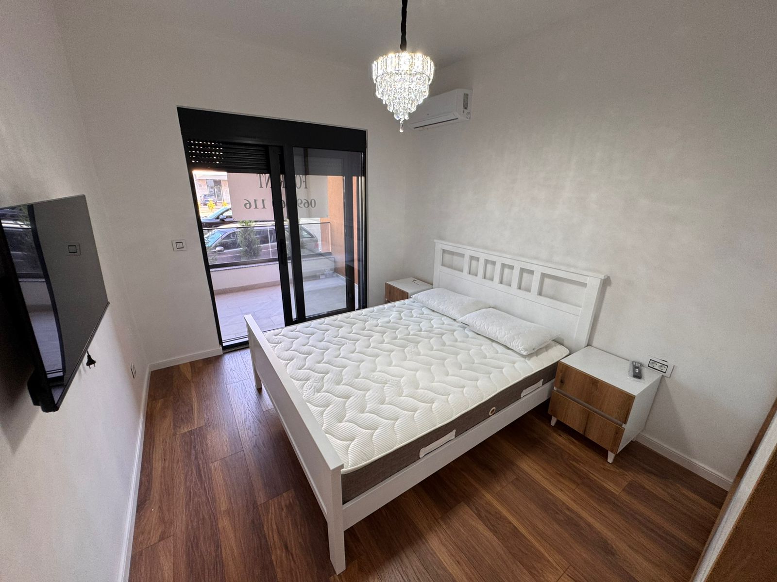 Modern Ulcinj bedroom with double bed, AC, TV, chandelier, and balcony access&mdash;prime real estate by immobilien.ekosphere.me/Ekosphere doo.