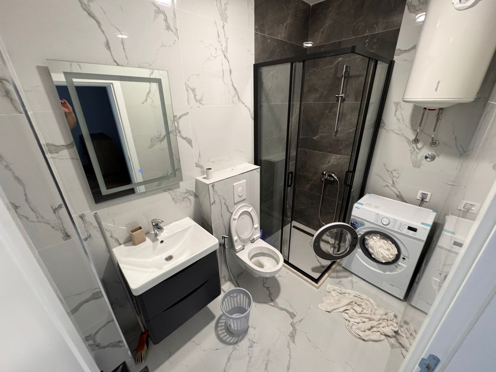 Sleek Ulcinj bathroom: white marble, glass shower, wall toilet, washer, premium amenities&mdash;ideal Montenegro investment. Eksophere doo project.