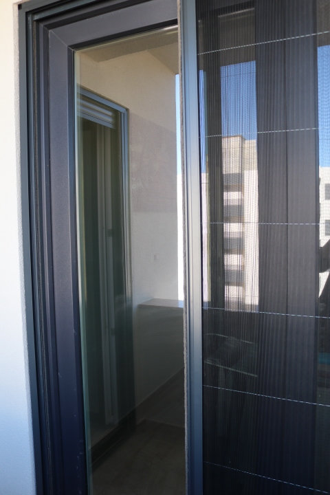 Modern sliding glass door with mesh screen opens to balcony; enjoy Ulcinj views. Exclusive via immobilien.ekosphere.me by ekosphere doo.