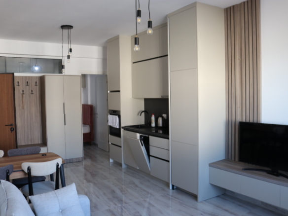 Modern Ulcinj apartment: light cabinetry, built-ins, designer lighting, wall TV, dining set, gray sofa. Exclusive at immobilien.ekosphere.me by ekosphere doo.