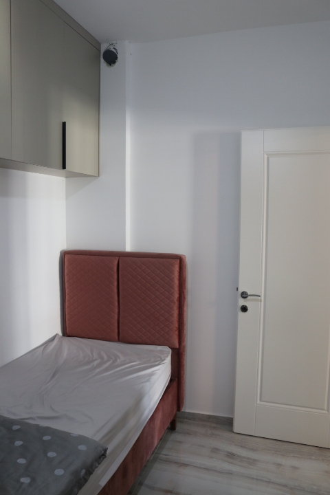 Charming Ulcinj bedroom with single bed, stylish red headboard, sleek storage, ideal for investment. Montenegro-listings.me by ekosphere doo.