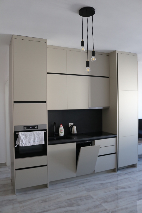 Sleek modern kitchen in Ulcinj, Montenegro: beige cabinets, black counters, oven, open dishwasher. Listed on immobilien.ekosphere.me by ekosphere doo.