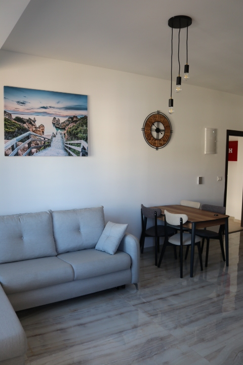 Elegant Ulcinj apartment: modern living room, gray sofa, marble floors, dining area. Invest at immobilien.ekosphere.me by ekosphere doo.