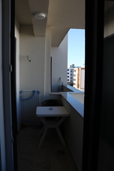 Charming Ulcinj balcony with white table, chair, and drying rack. Enjoy blue sky views&mdash;exclusive listing by ekosphere doo on immobilien.ekosphere.me.