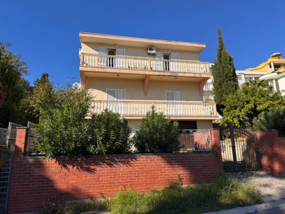 Premium three-story beige house in Ulcinj with 2 balconies, lush greenery, brick fence. Top Montenegro investment at immobilien.ekosphere.me by ekosphere doo.