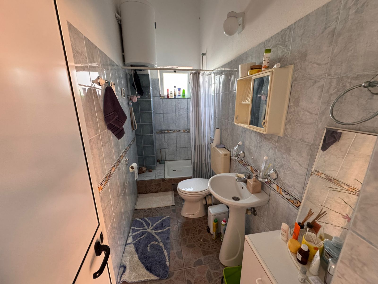Modern tiled bathroom in Ulcinj, with shower, storage, and fixtures&mdash;ideal Montenegro real estate investment at immobilien.ekosphere.me by ekosphere doo.