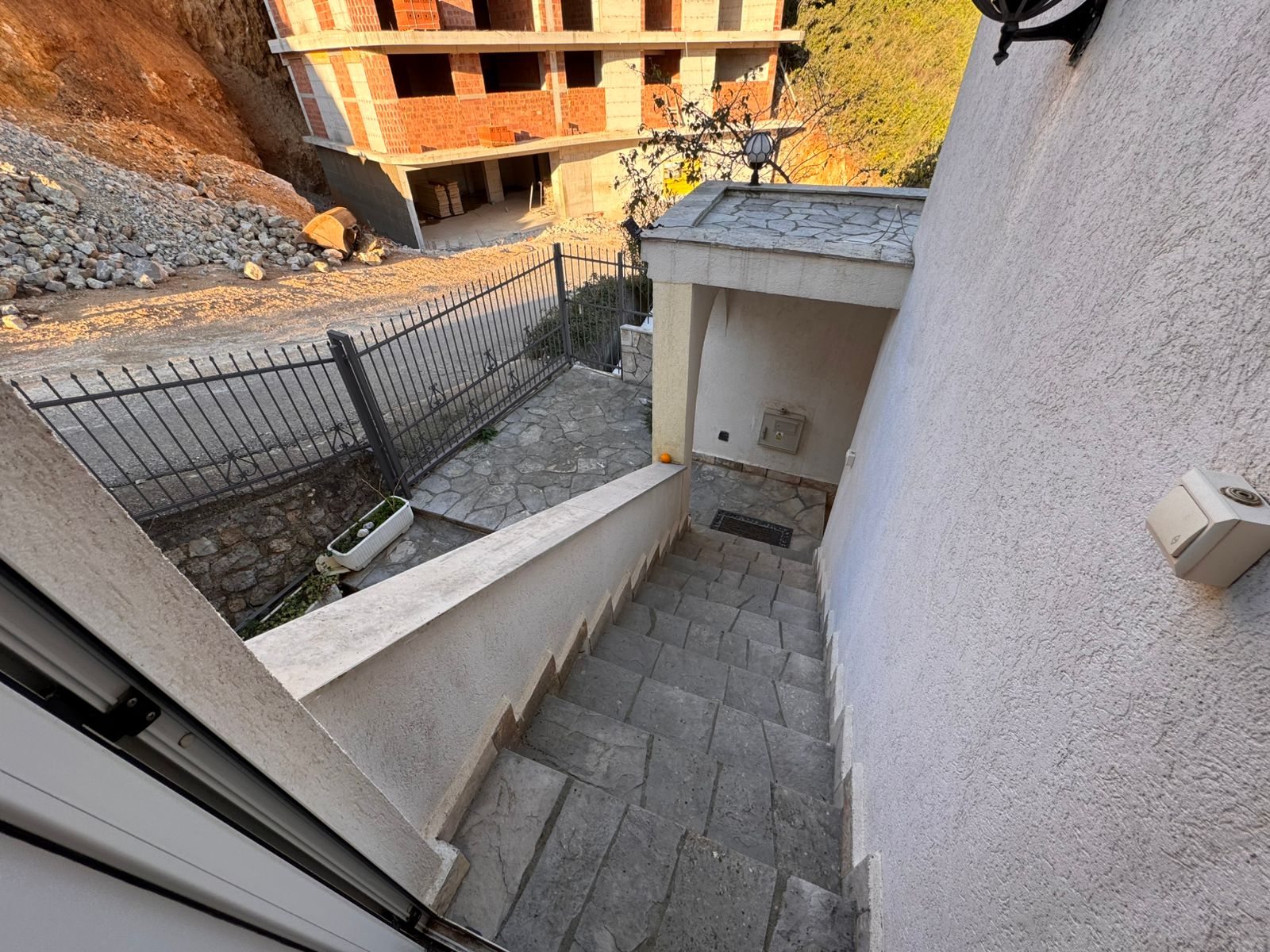 Elegant stone staircase descends to gated entry, overlooking new development potential in Ulcinj. Exclusive on immobilien.ekosphere.me by ekosphere doo.