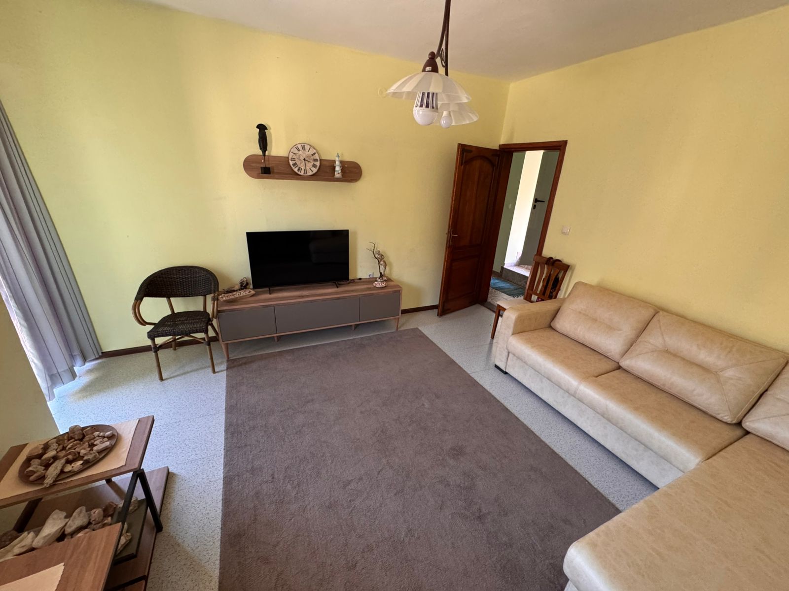 Bright Ulcinj living room with yellow walls, stylish beige sofa, modern TV, and quality finishes. Invest via immobilien.ekosphere.me by ekosphere doo.