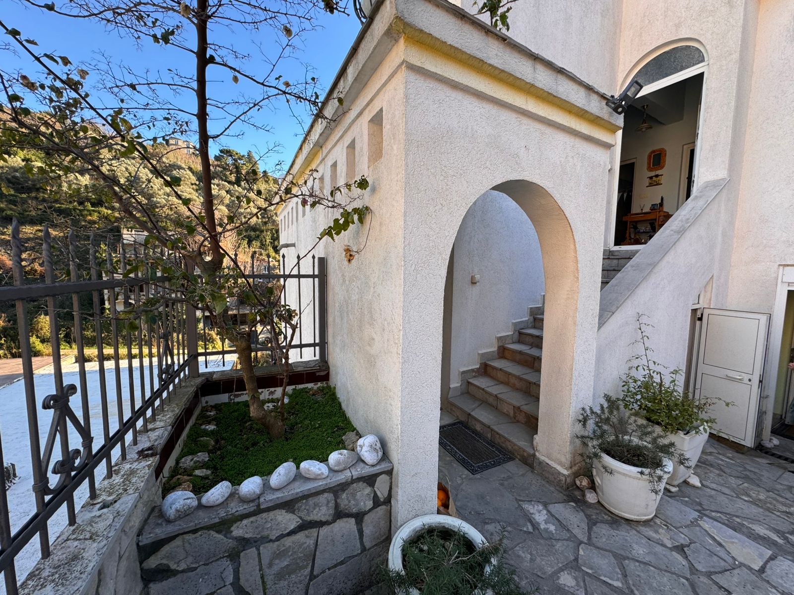 Prime Ulcinj property: Elegant white residence with arched entry, stone steps, garden, and secure fence. Invest via immobilien.ekosphere.me by ekosphere doo.