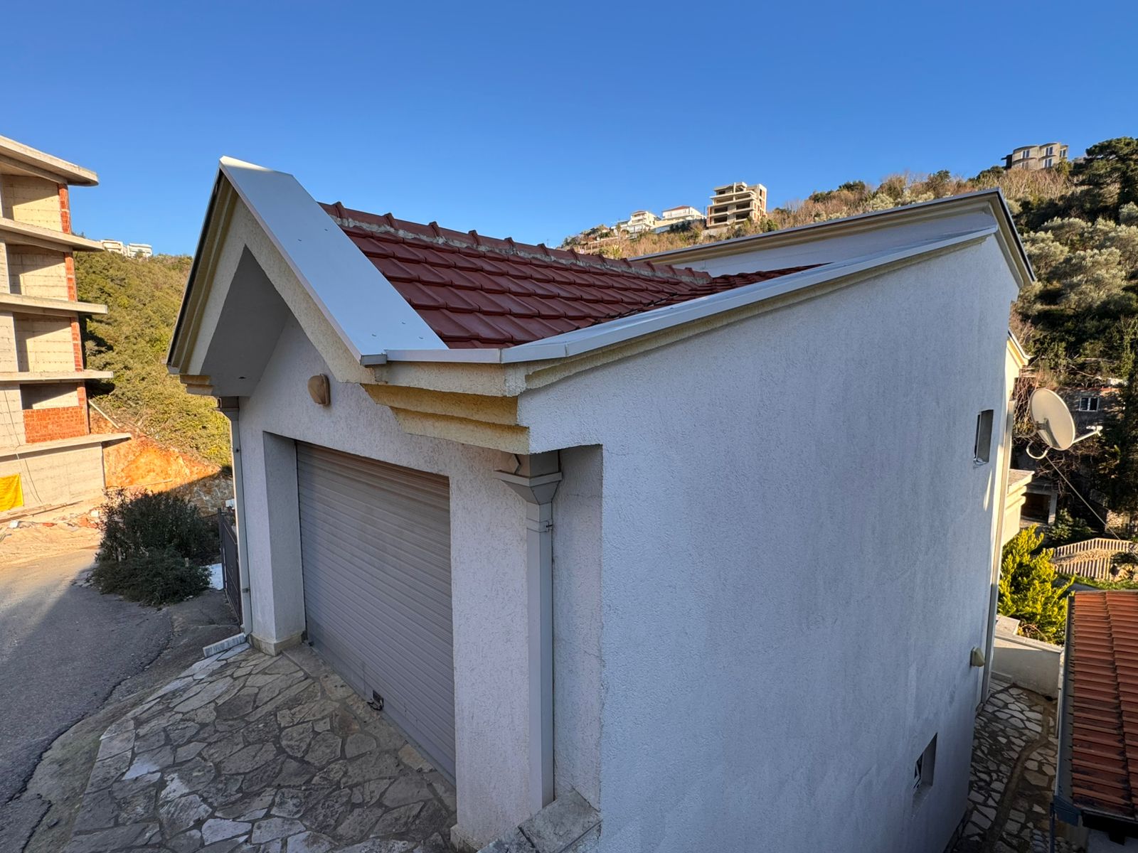 Charming white home with red-tiled roof, stone driveway, and garage in scenic Ulcinj hills. Exclusive at immobilien.ekosphere.me by ekosphere doo.