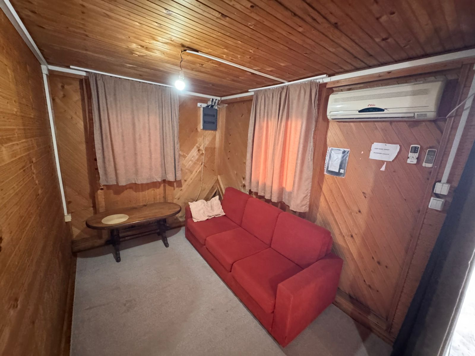 Charming Ulcinj studio: wood accents, modern AC, cozy red sofa, bright windows. Prime Montenegro investment&mdash;exclusive on immobilien.ekosphere.me by ekosphere doo.