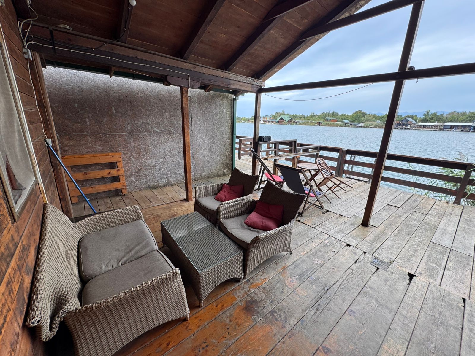 Elegant covered wooden deck with premium wicker seating, glass-top table, and stunning water views in Ulcinj&mdash;exclusive at immobilien.ekosphere.me by ekosphere doo.