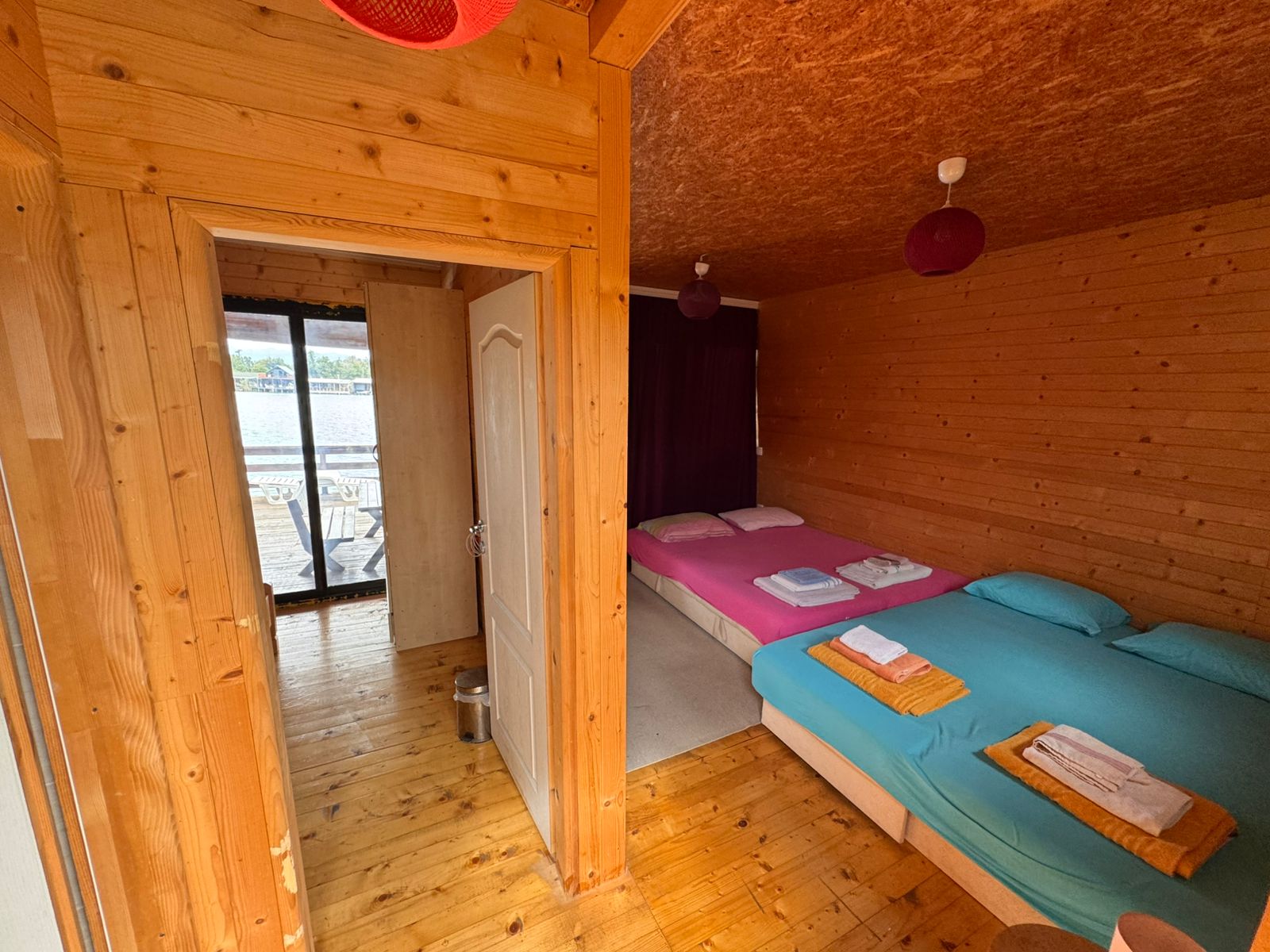 Charming Ulcinj wooden cabin with open-plan interior, twin beds, vibrant bedding, scenic views&mdash;exclusive on immobilien.ekosphere.me by ekosphere doo.