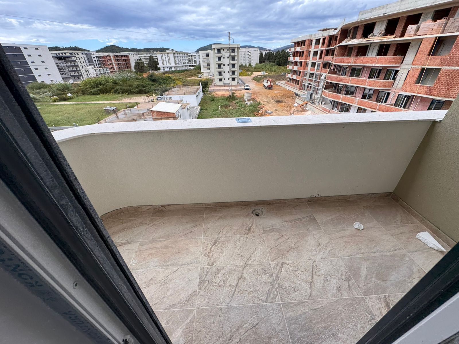Modern tiled balcony with elegant curved railing, overlooking new development in Ulcinj. Prime Montenegro investment by ekosphere doo.