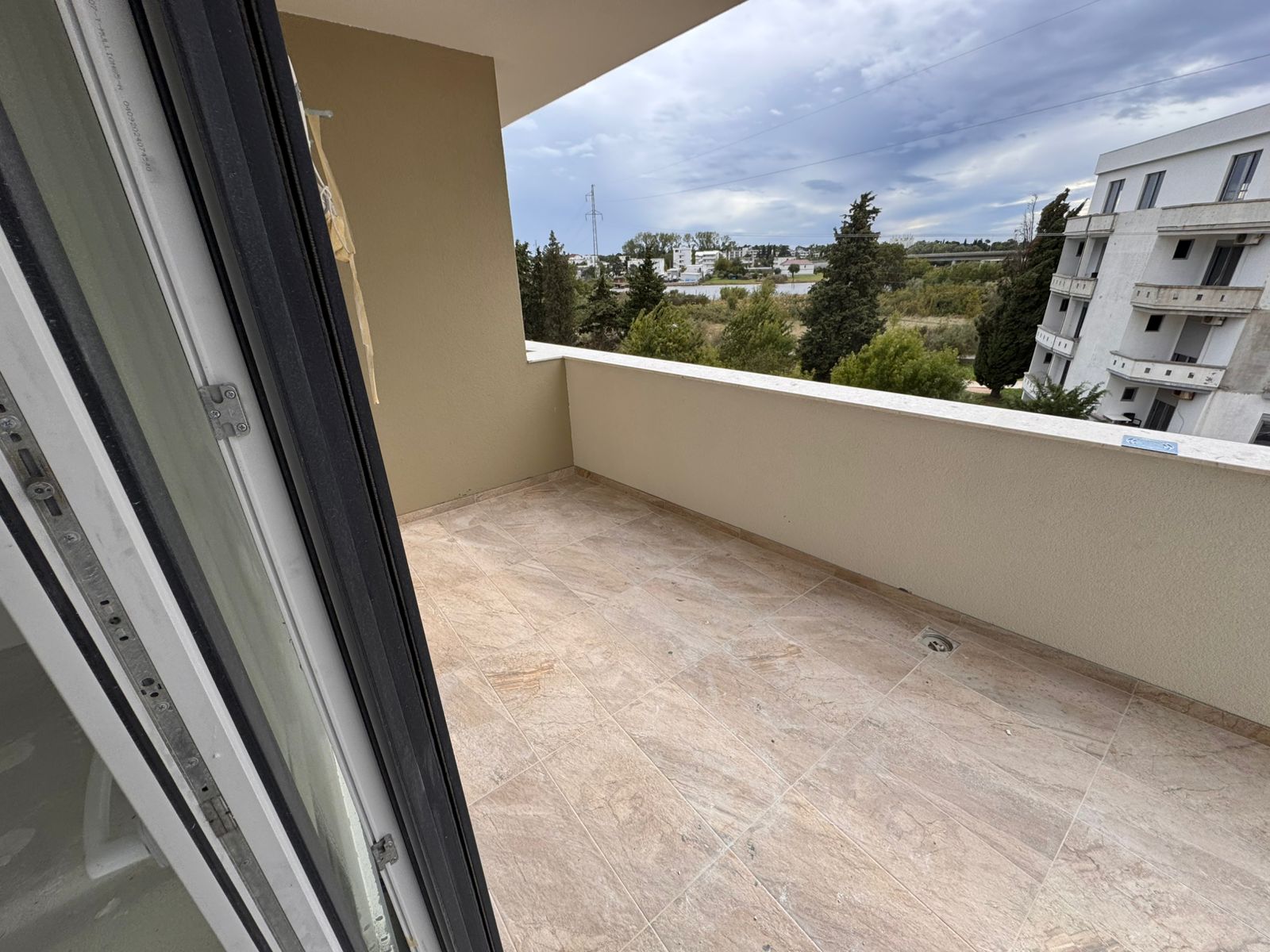 Spacious tiled balcony with beige walls, open views to greenery and nearby apartments&mdash;prime Ulcinj real estate by immobilien.ekosphere.me.