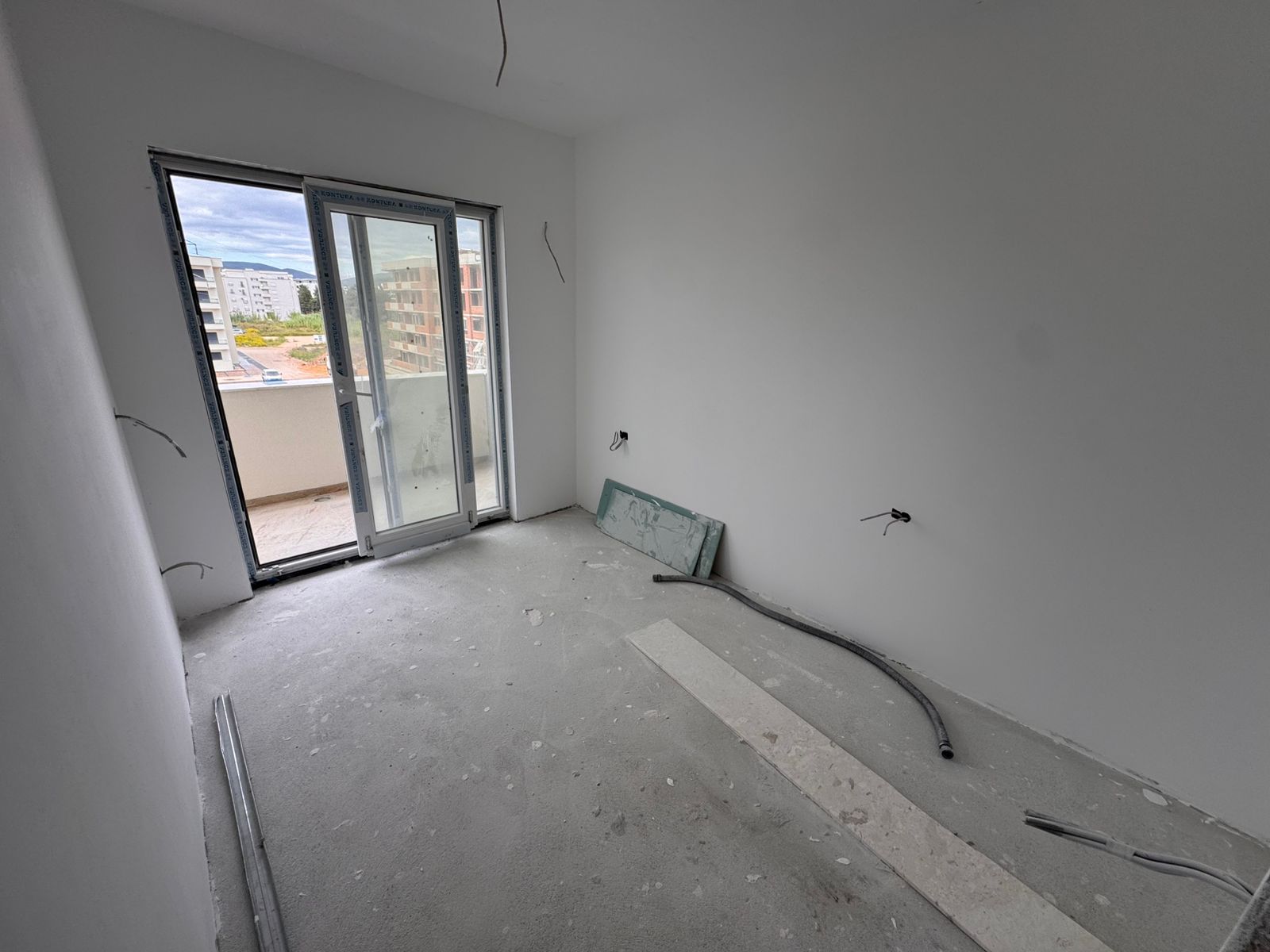 Spacious unfinished apartment in Ulcinj with white walls, large glass balcony door, and investment potential&mdash;exclusive to immobilien.ekosphere.me.