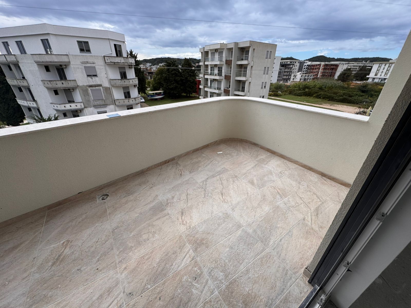 Spacious tiled balcony in Ulcinj with beige floors, cream walls, modern views&mdash;ideal Montenegro investment. View at immobilien.ekosphere.me by ekosphere doo.