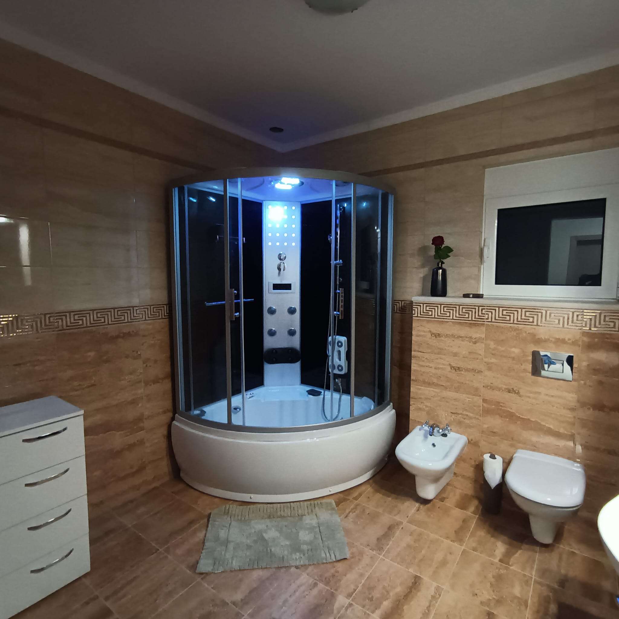 Elegant Ulcinj bathroom with tan tiles, blue-lit shower, premium fixtures&mdash;exclusive Montenegro investment via immobilien.ekosphere.me.