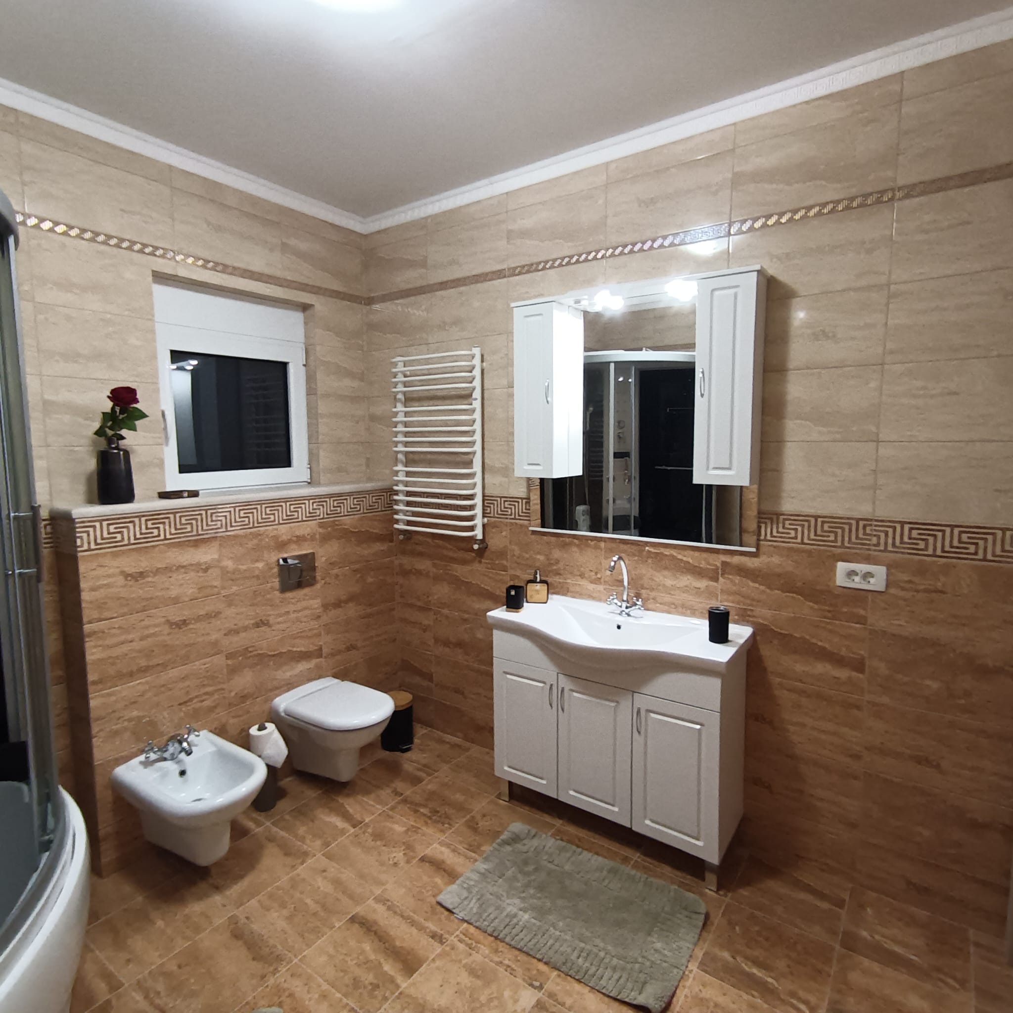 Modern Ulcinj bathroom with beige tiles, premium fixtures, window, and chic vanity&mdash;exclusive listing on immobilien.ekosphere.me by ekosphere doo.