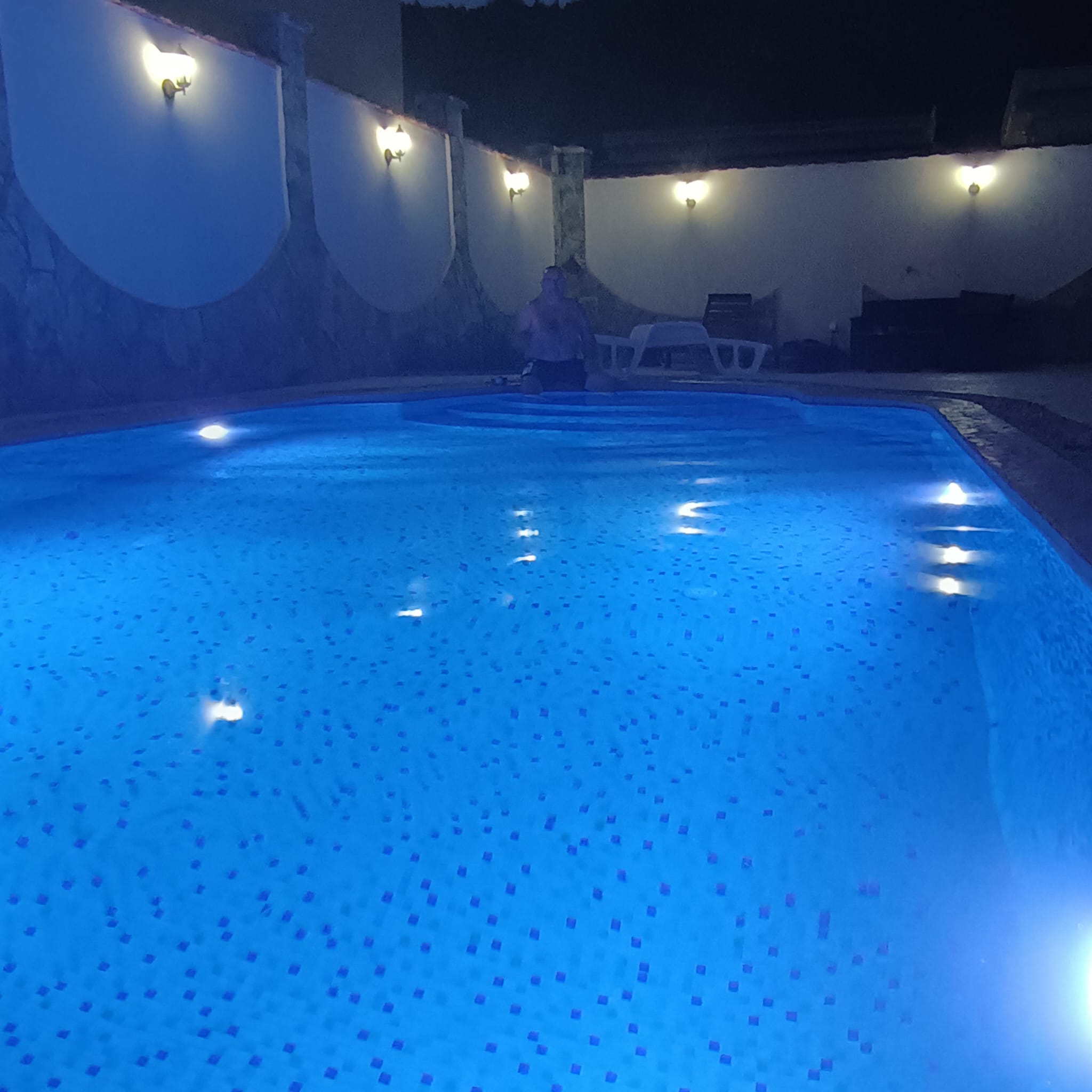 Stunning Ulcinj villa: illuminated pool, elegant stone walls, luxe lounge chair. Invest in Montenegro with immobilien.ekosphere.me.