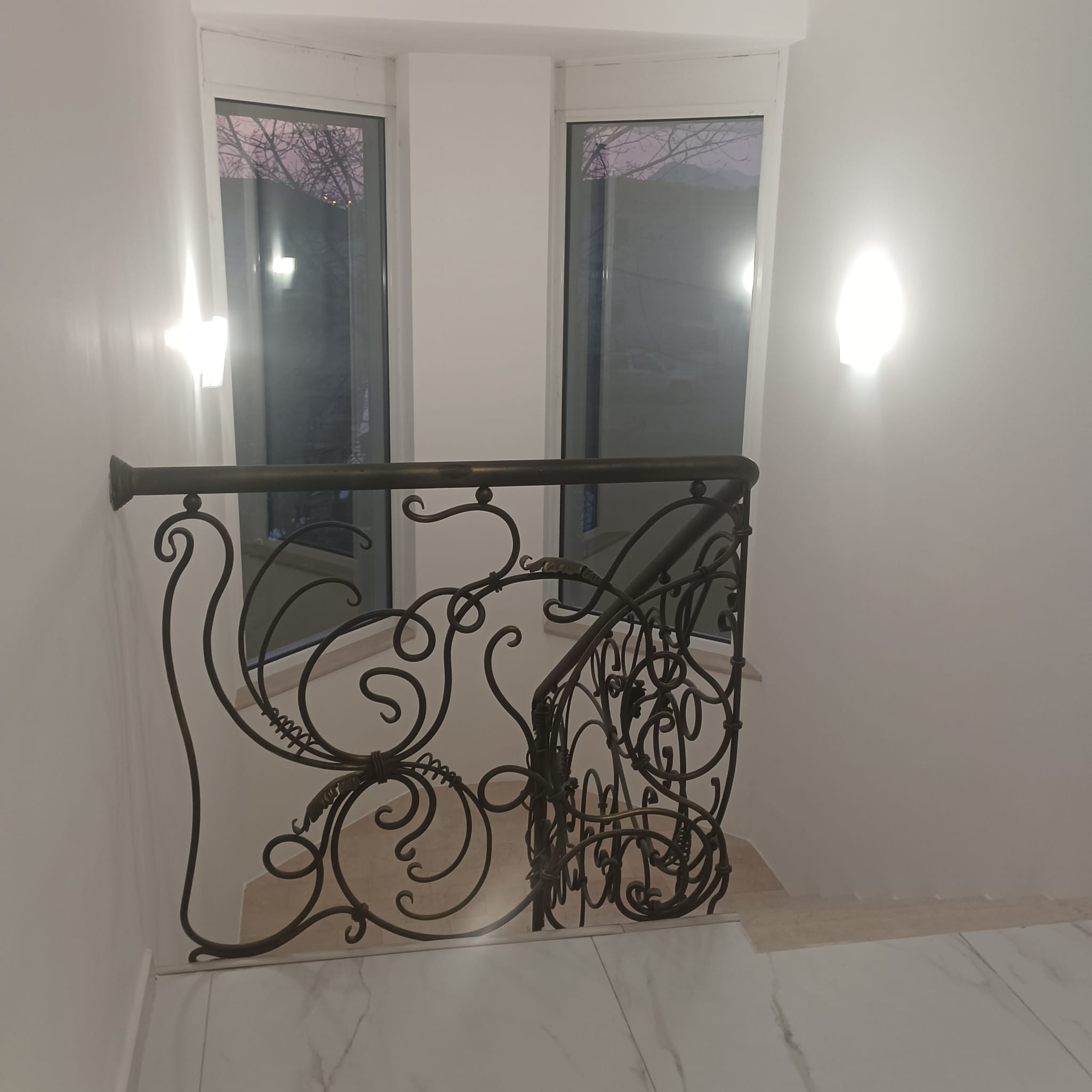 Elegant staircase with ornate metal railing, modern lighting, and floor-to-ceiling windows&mdash;prime Ulcinj property on immobilien.ekosphere.me by ekosphere doo.