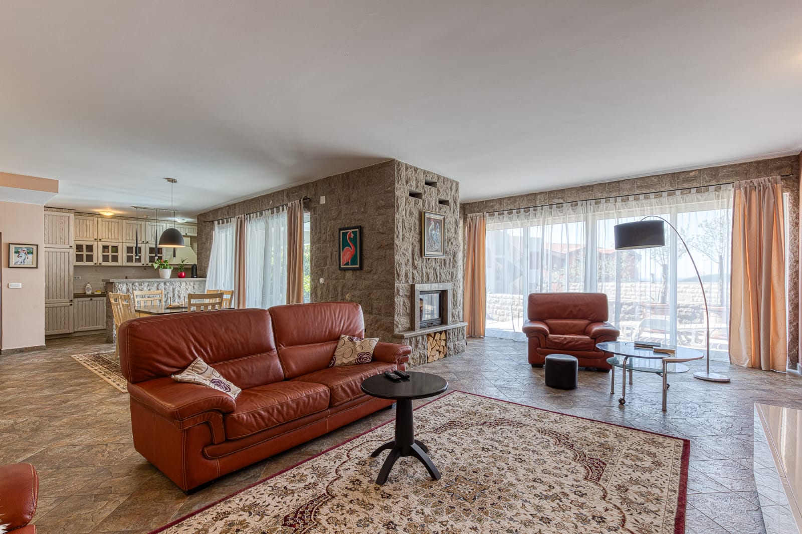 Elegant Ulcinj living room: brown leather sofas, stone feature wall, large windows. Ideal Montenegro investment&mdash;immobilien.ekosphere.me by ekosphere doo.
