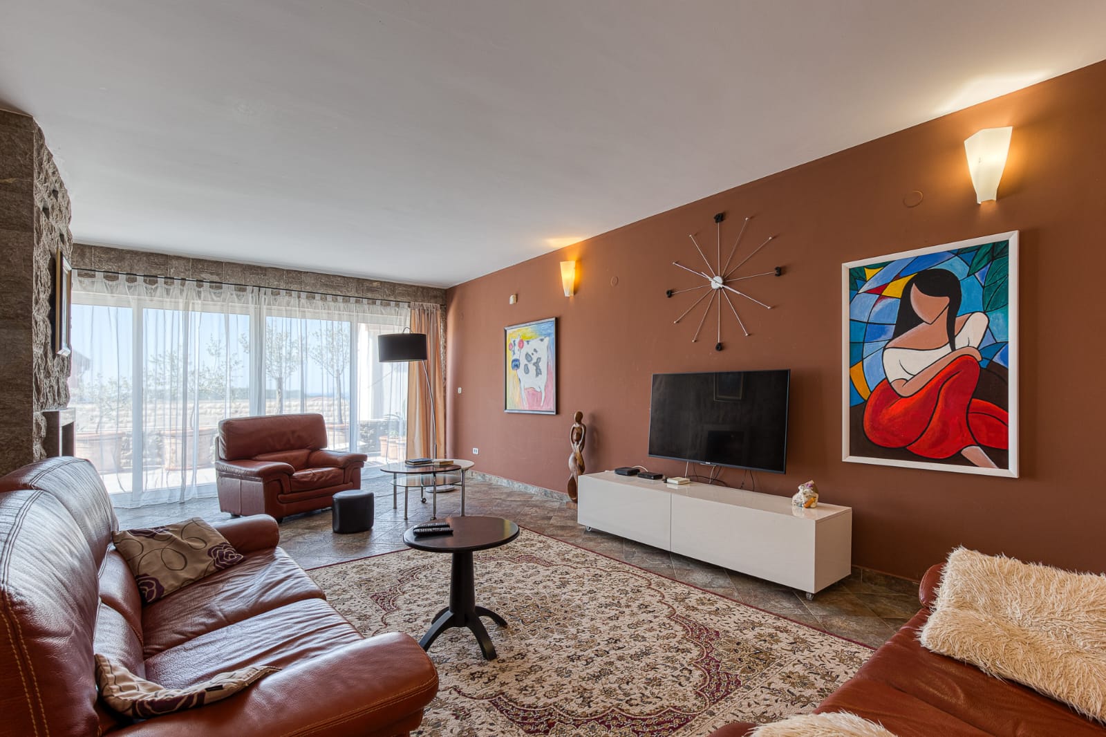 Elegant Ulcinj living room: brown leather sofas, modern art, large windows, ideal Montenegro real estate via immobilien.ekosphere.me by ekosphere doo.