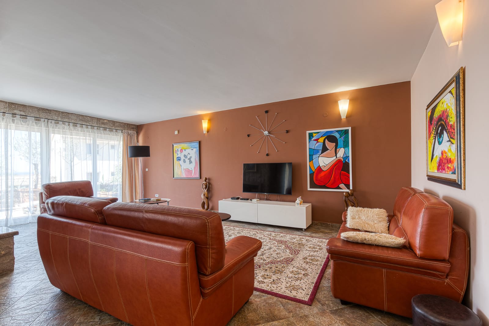 Stylish Ulcinj living room: brown leather sofas, large windows, premium details. Invest in Montenegro real estate at immobilien.ekosphere.me by ekosphere doo.