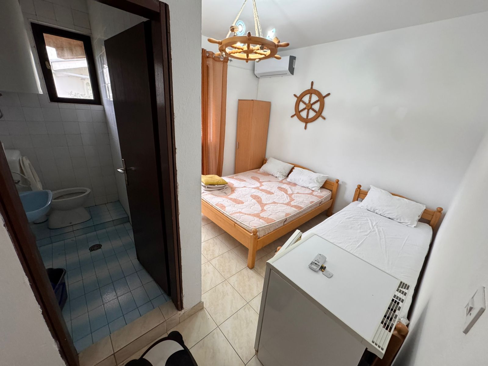 Charming Ulcinj hotel room: double & single beds, mini fridge, unique decor, ensuite with blue tiles. Invest via immobilien.ekosphere.me.