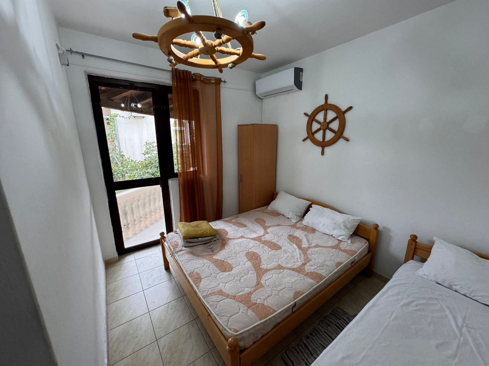 Charming Ulcinj bedroom with double and single beds, nautical details, and private glass door&mdash;ideal Montenegro real estate investment.