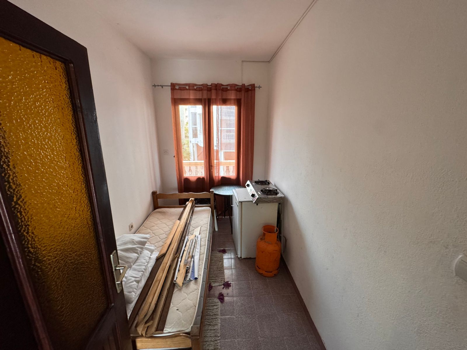 Bright, compact room in Ulcinj with bed, stove, and window&mdash;ideal Montenegro investment. Listed on immobilien.ekosphere.me by ekosphere doo.