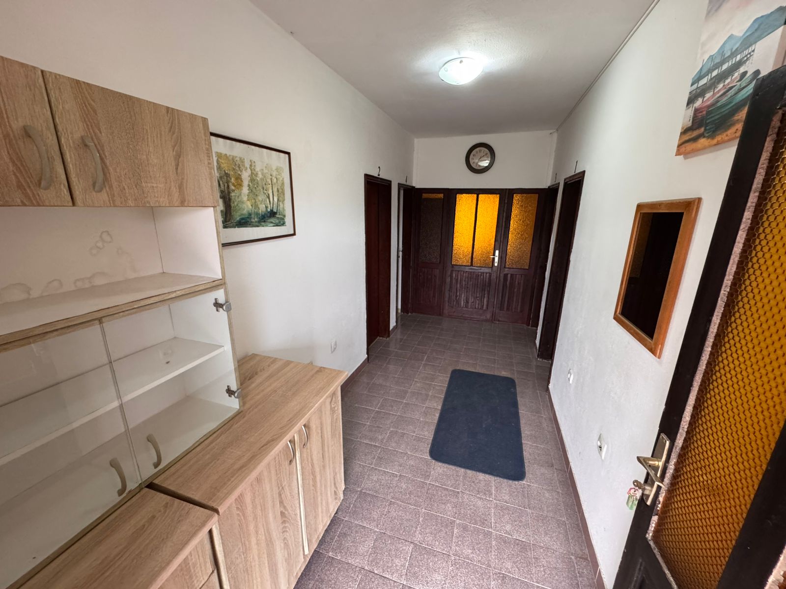 Elegant Ulcinj hallway with brown tiled floors, wood cabinets, art accents&mdash;ideal Montenegro investment via immobilien.ekosphere.me by ekosphere doo.