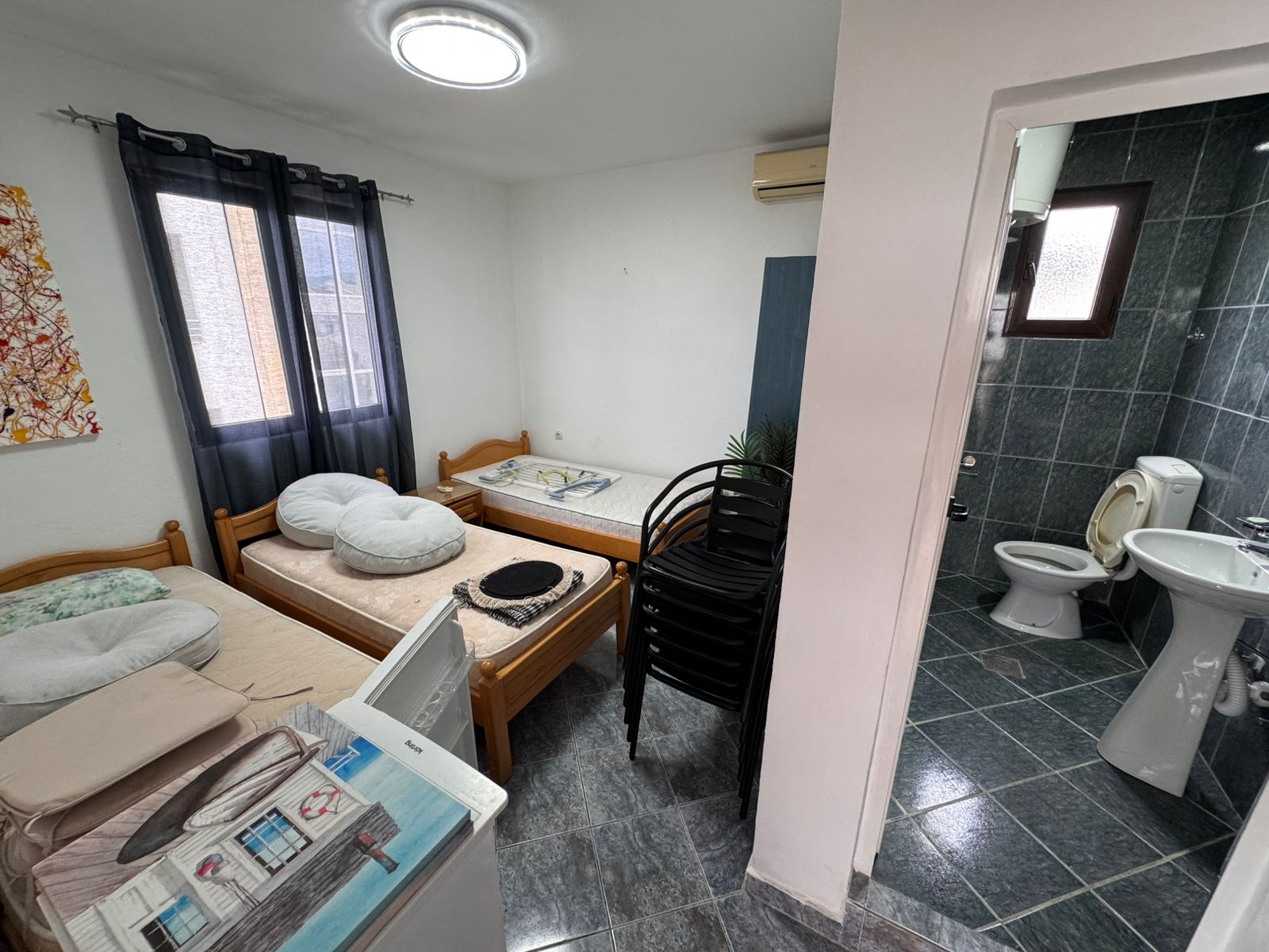 Cozy Ulcinj investment: compact room with twin beds, window, A/C, ensuite green-tiled bath. See more on immobilien.ekosphere.me by ekosphere doo!.