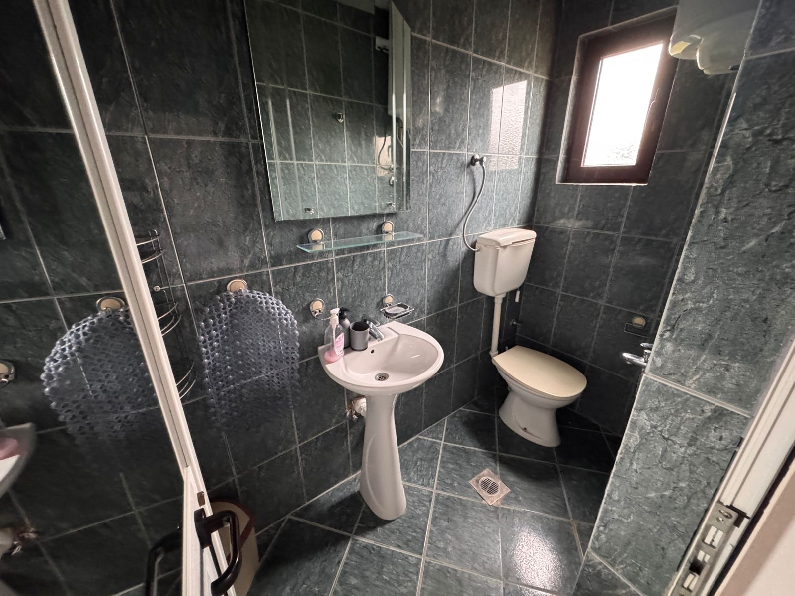 Stylish bathroom with elegant dark green tiles, modern fixtures, natural light&mdash;prime Ulcinj investment via immobilien.ekosphere.me by ekosphere doo.