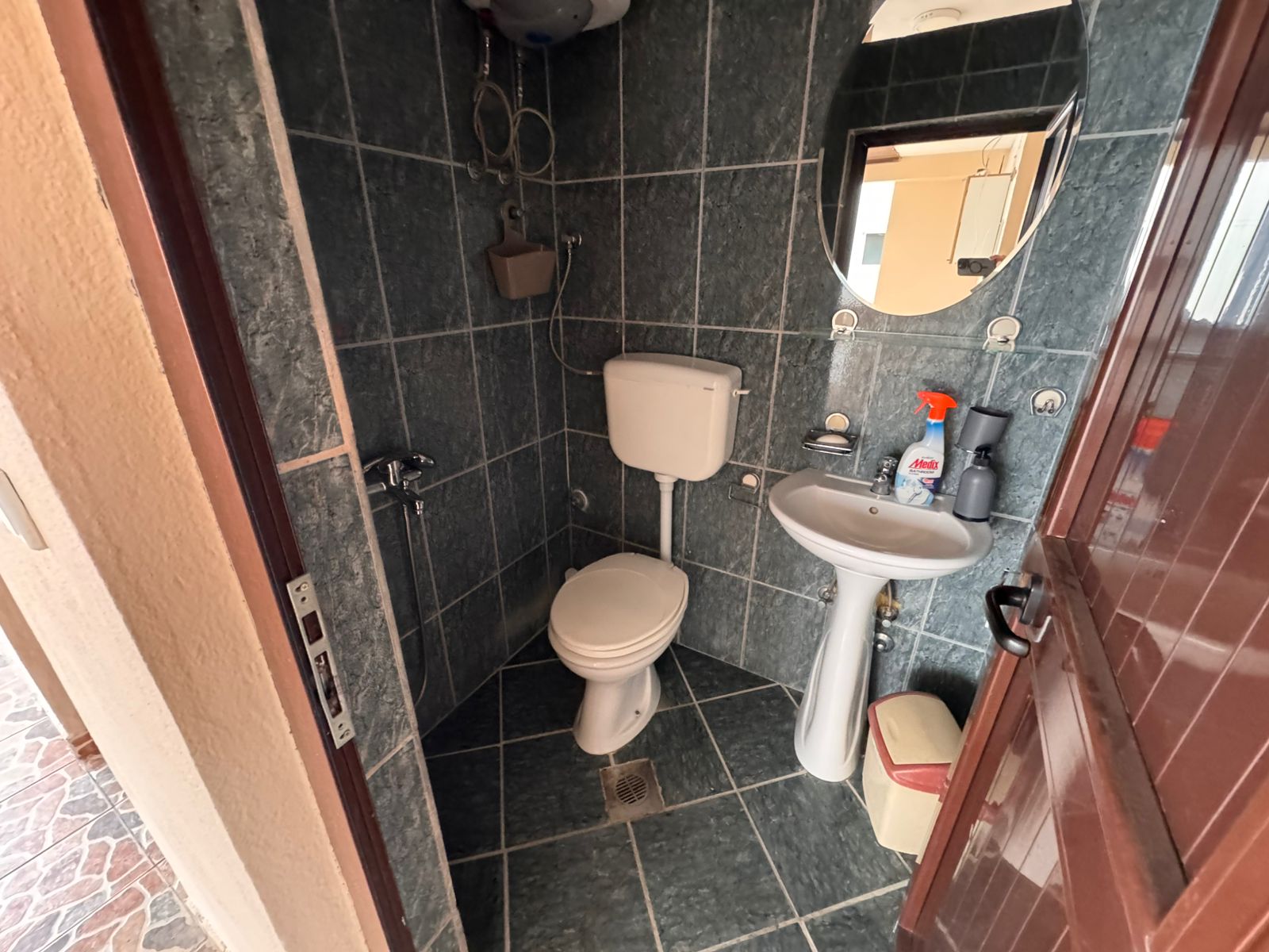 Modern tiled bathroom in Ulcinj with toilet, pedestal sink, mirror, water heater; prime real estate on immobilien.ekosphere.me by ekosphere doo.