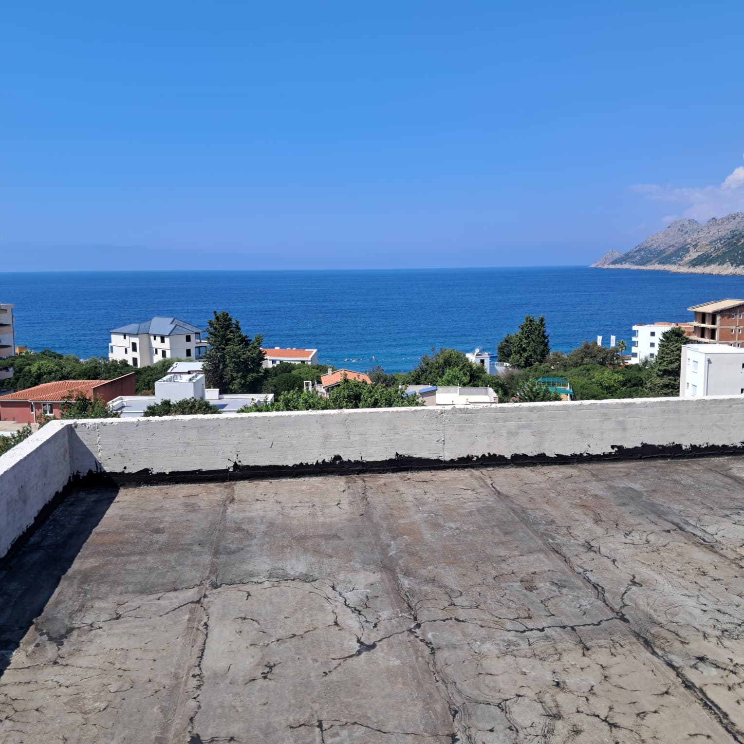 Panoramic rooftop view over Ulcinj: residential homes, lush greenery, Adriatic Sea&mdash;prime Montenegro real estate by ekosphere doo.