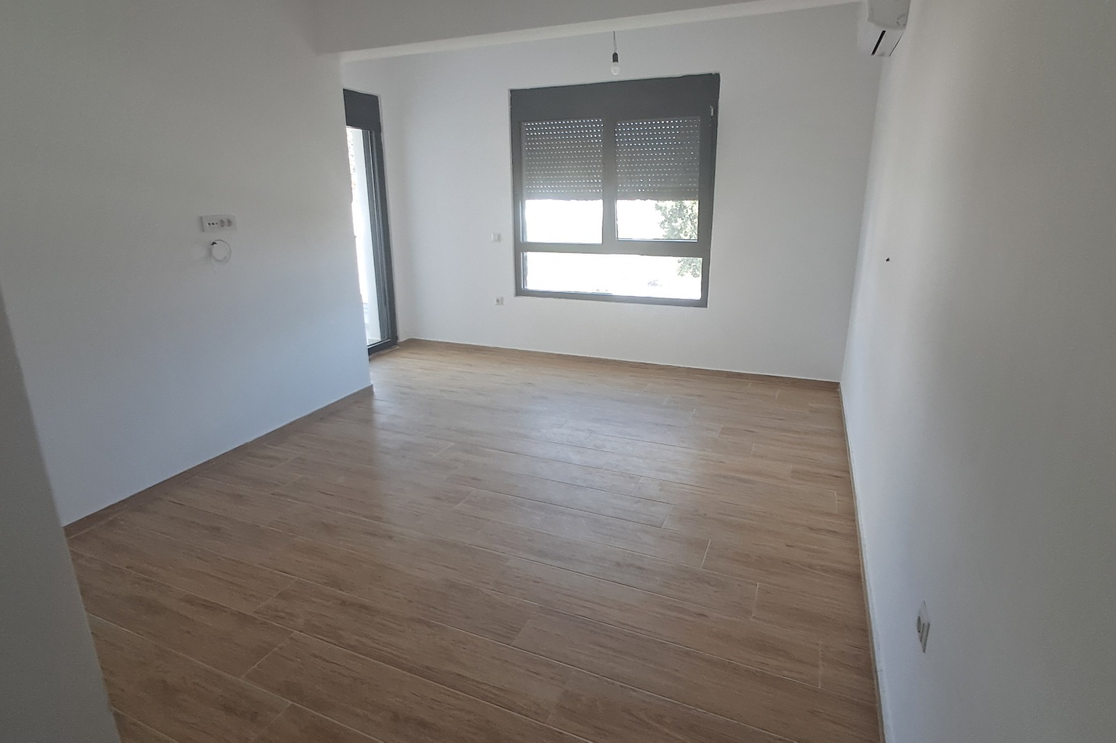 Modern, bright room in Ulcinj with wood-look tile floors, AC, balcony access&mdash;ideal Montenegro investment via immobilien.ekosphere.me by ekosphere doo.