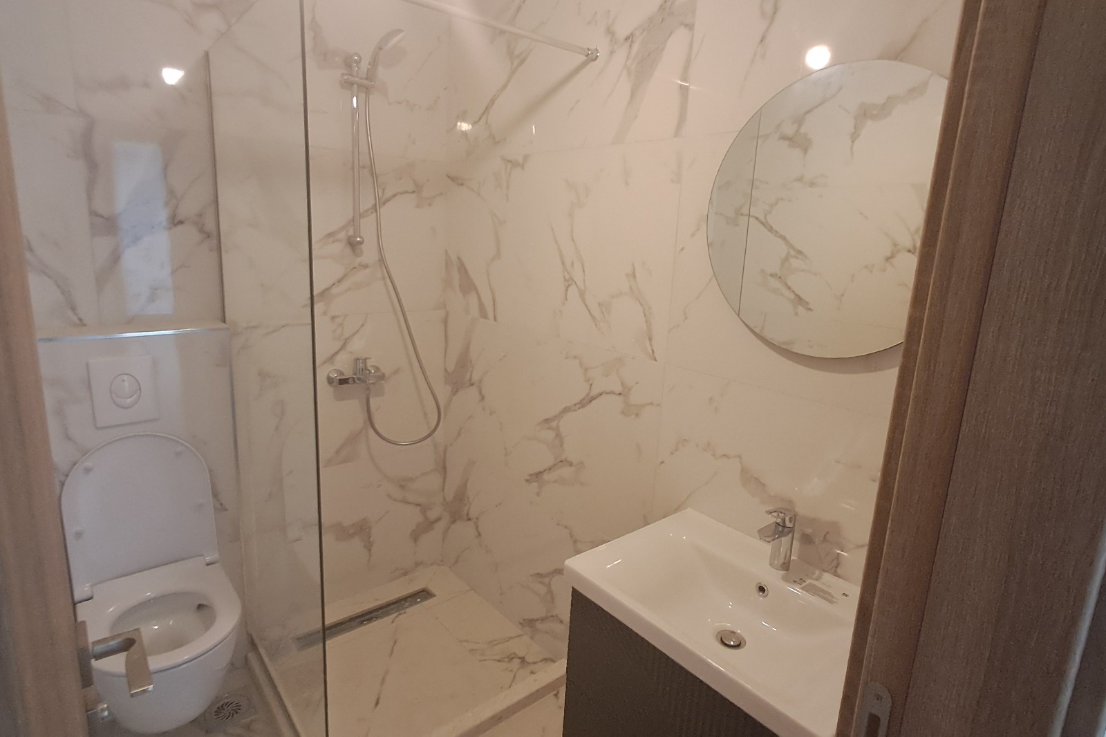 Modern bathroom in Ulcinj with marble-patterned walls, walk-in shower, and premium finishes&mdash;exclusive Montenegro-listings.me by ekosphere doo.