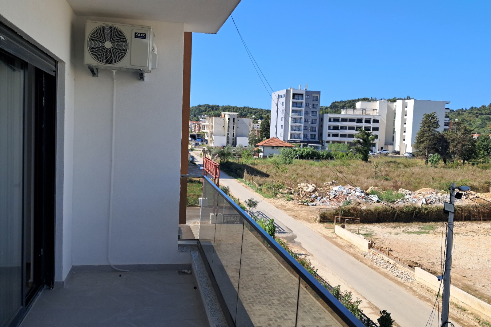 Modern balcony view with glass railing, air conditioning, and cityscape&mdash;prime Ulcinj investment on immobilien.ekosphere.me by ekosphere doo.
